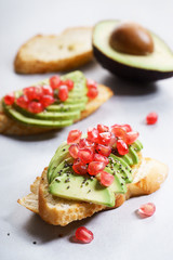 sliced avocado on toast bread with pomegranate seeds.