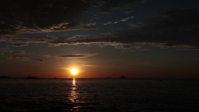 Sunrise sky fishing boats and a tropical island at dawn looking out over the south China sea in Vietnam. High definition time lapse stock footage.