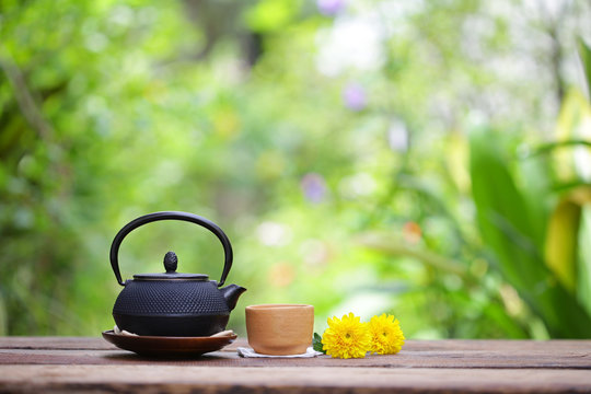 Old black tea pot with brown cup and flower