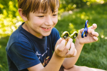 Boy playing with two fidget spinner stress relieving toys outdoor