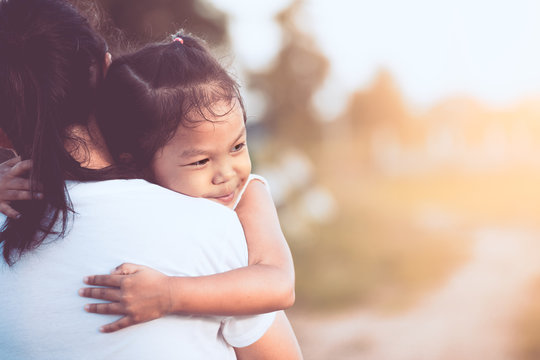 happy asian little child girl hugging her mother with love in the field in vintage color tone