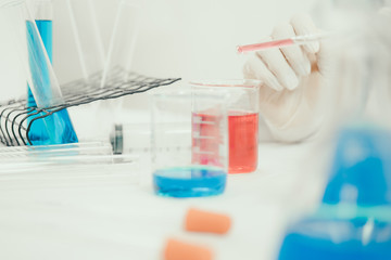 Young Asian scientist working in the lavatory with test tubes and other equipment to discover new drugs, products and methods of formulation