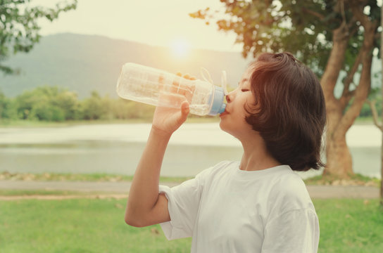  girl drinking water after exercise in park