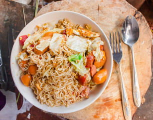 spicy noodle in bowl and ingredients on wood background top view