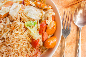 spicy noodle in bowl and ingredients on wood background top view