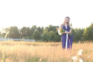 Naklejka premium Russian girl in national dress stay on filed in sunset light