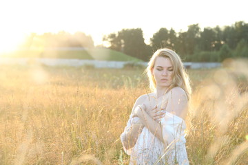 Fototapeta na wymiar Sunset in the field - Beautiful girl on the grass