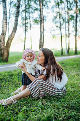 Funny mom with baby sitting on the grass