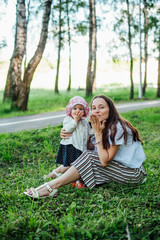 Fototapeta premium Funny mom with baby sitting on the grass