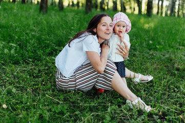 Funny mom with baby sitting on the grass
