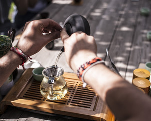 Traditional Chinese tea ceremony - hands holding a clay tea pot and pouring tea