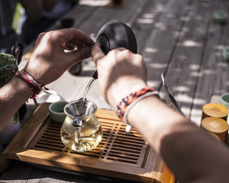 Traditional Chinese tea ceremony - hands holding a clay tea pot and pouring tea