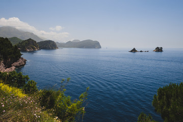 Shoreline and Adriatic sea scenic landscape on the coast path to Petrovac, Montenegro. Rocks, water and Sveta Nedjelja island by sunset on the way from Perazica Do to Petrovac near Rezevici village.