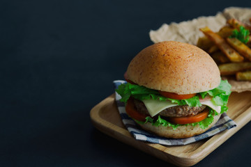 Homemade hamburger on plaid napkin with french fries. Delicious sandwich hamburger with meat or pork ham cheese and fresh vegetable. Hamburger or sandwich is the popular fast food for brunch or lunch.