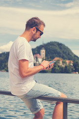 Man sitting on the dock and using a cellphone.