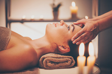 Spa facial massage. Brunette woman enjoying relaxing face massage in beauty spa salon