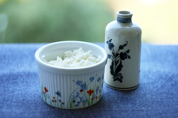 Fototapeta na wymiar Food. Cottage cheese in a plate, a milk jug and on a table with a blue tablecloth.