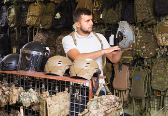 Young guys choosing helmet in military shop