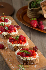 Fruit brusquest with raspberry and cottage cheese on a wooden board