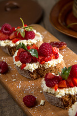 Fruit brusquest with raspberry and cottage cheese on a wooden board