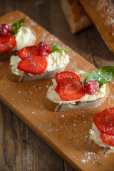 Fruit brusquest with raspberry and cottage cheese on a wooden board