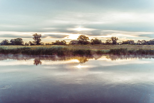 Magnificent sunrise on the river in the summer with fog over the water