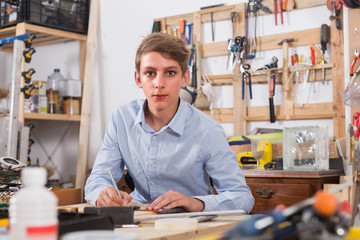 teenager  smiling and working with wood in the workshop