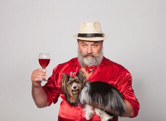 Glamorous Elderly man with beard in red shirt with yorkshire terrier on white background in studio