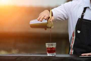 bartender workplace. bartender on the street catering bar preparing a coctail in a glass in rays of the sun, selective focus, copyspace. Concept of preparation, service and vacation