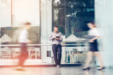 Businessman using a digital tablet office outdoors and Blurred People Walking in Front of Modern...