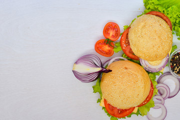 Hamburger with cheese, meat, tomatoes and onions and herbs. On Wooden background. Top view. Free space.