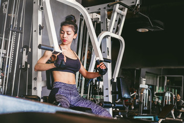 Fototapeta na wymiar Asian young fitness woman execute exercise with exercise-machine in gym