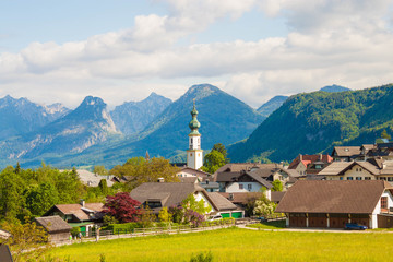 Alpine village St. Gilgen with a church, mountains on background. Summer landscape of countryside, Austria.
