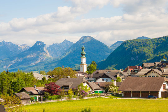 Alpine village St. Gilgen with a church, mountains on background. Summer landscape of countryside, Austria.