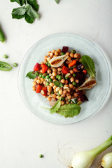 Fresh chickpea salad with mint and vegetables on white rustic background. Healthy lunch concept.  Composition with copy space
