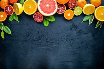 Fresh citrus fruits. Lemon orange, tangerine, lime. On a black background Wooden. Top view.