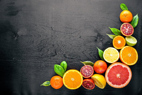 Fresh citrus fruits. Lemon orange, tangerine, lime. On a black background Wooden. Top view.