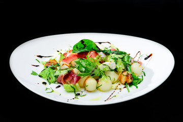 classic Italian summer delicious fresh salad with cheese, parma ham and soy sauce on white plate,...