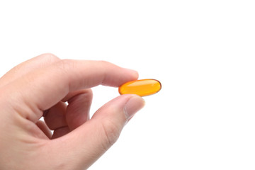 Close up to fish oil capsule in fingers on white background