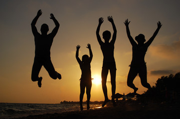 Family jumping on a beach at sunset. Happy family on the sea. Summer vacation concept