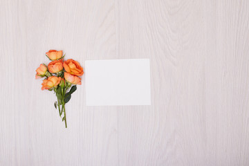 Creative mock up layout made of roses  with copy space on table homemade flat lay. Empty sheet of paper. Mockup with a card and orang rose