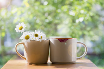 Two mugs nearby. One of daisies, the other with prints of lipstick. The concept of the solar in the morning. The summer mood.