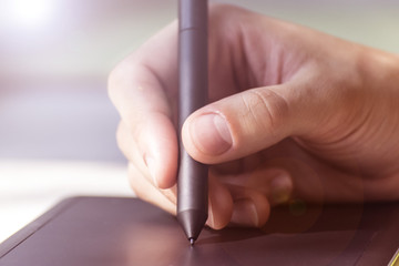 Hand of a young man writes on a graphics tablet