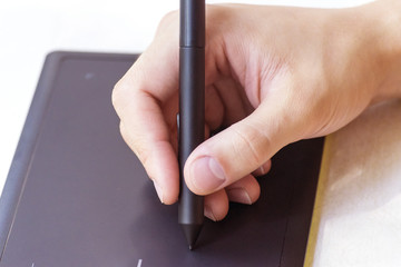 Hand of a young man writes on a graphics tablet