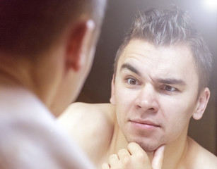Fototapeta premium The young man looks at himself in the mirror