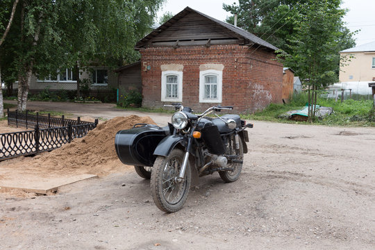 Motorcycle with a stroller on the background of a brick old house