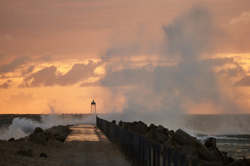 waves hitting the pier in front of the sunset at Nr. Vorupoer at the North Sea Coast in Denmark