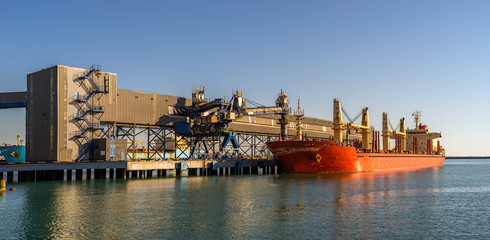 Bulk-carrier ship in a port panorama. Transportation and logistic