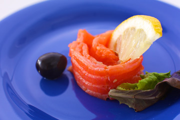 Slice of salmon with lemons and olives on a plate