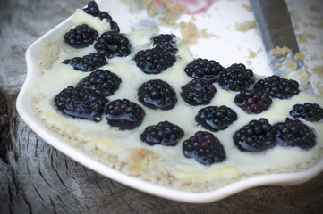 Dessert with blackberries in a plate with knife isolated on wooden background